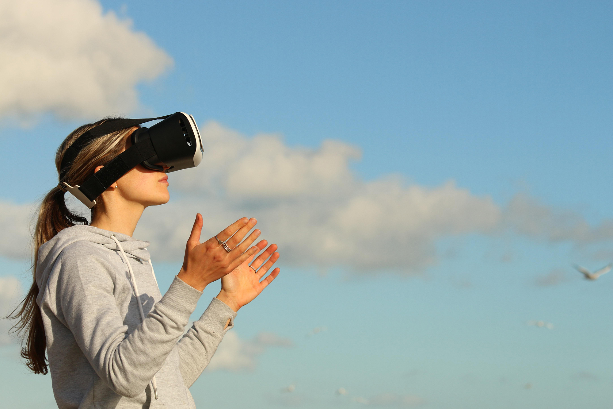Woman wearing a VR headset with a sky and clouds background
