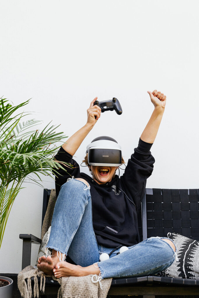 Woman cheering on the couch wearing a VR headset.